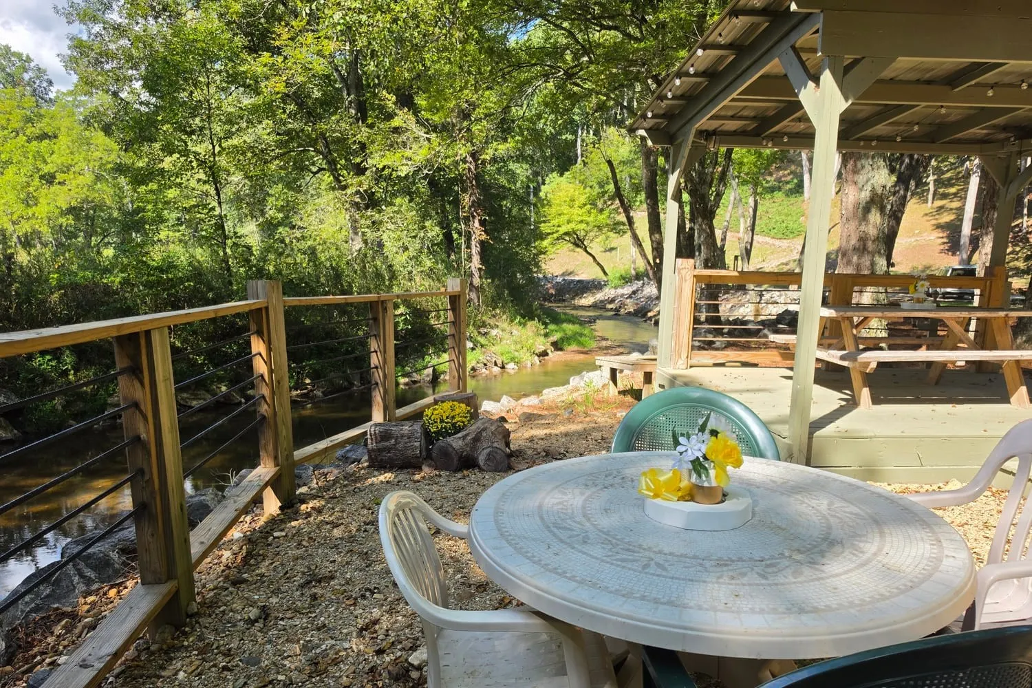 Table with flowers beside a creekside pavilion