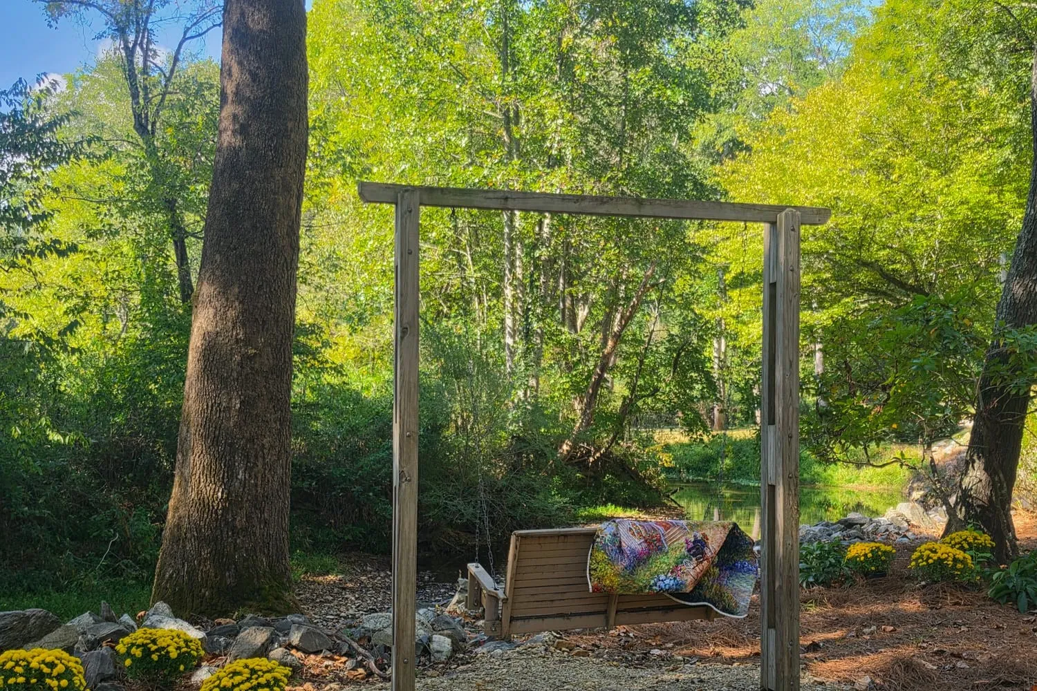 Quilt-draped porch swing beside Brasstown Creek